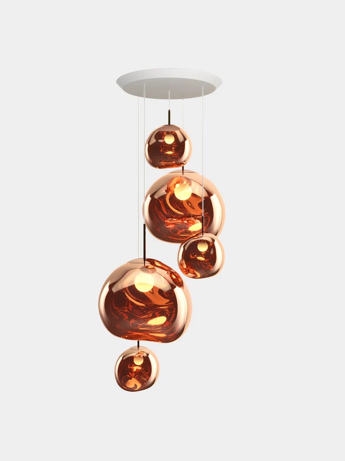 The Melt Mini Round Pendant System (Copy) showcases seven metallic copper-colored spherical bulbs suspended at different heights from a sleek white ceiling mount, adding a modern touch to any space.